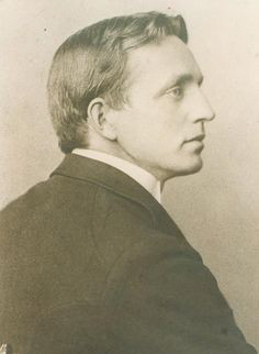 A black and white photo of a younger John Fox, Jr. He is seated in profile with his right side facing the camera. 