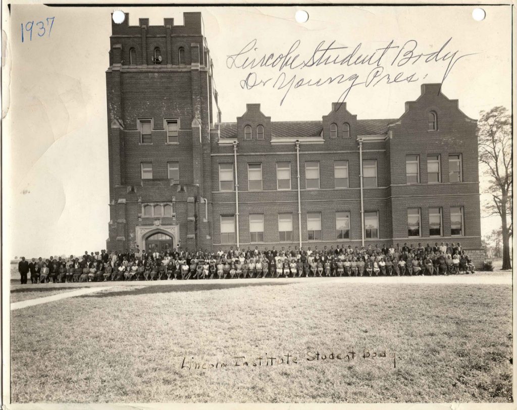 Black and white photo of a large brick building with a large group of people in front of it. Text on photo reads 1937 and Lincoln Student Body Dr. Young President.