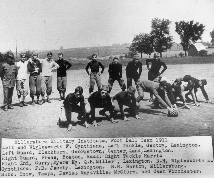 Black and white photo of 16 young men. Seven are kneeling on the ground with one man holding a football. Nine are standing in the background. Caption reads Millersburg Military Institute Football Team 1911